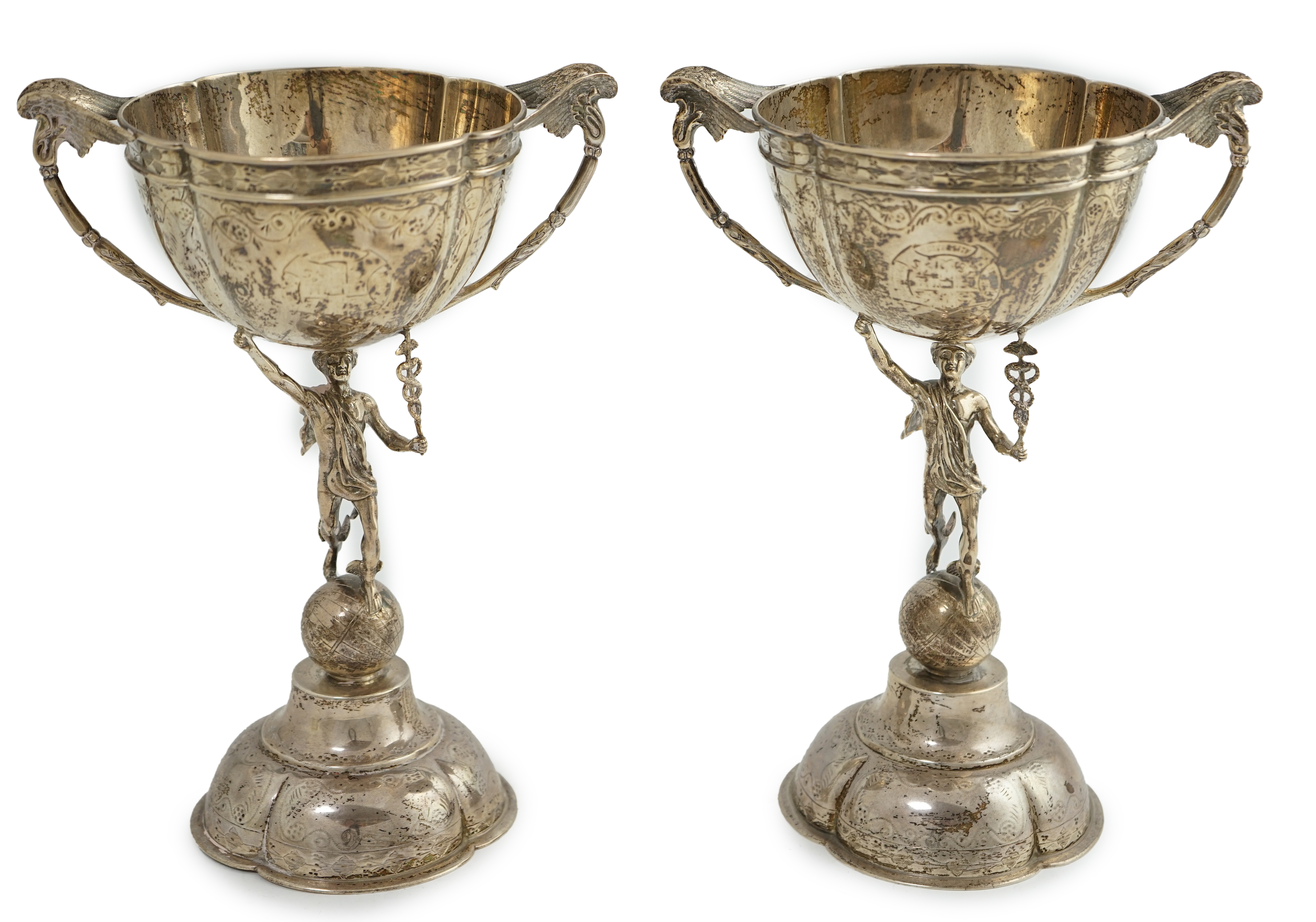 A pair of Victorian silver two handled pedestal cups, each figural stem modelled as Hermes upon a globe, by Edward Charles Brown